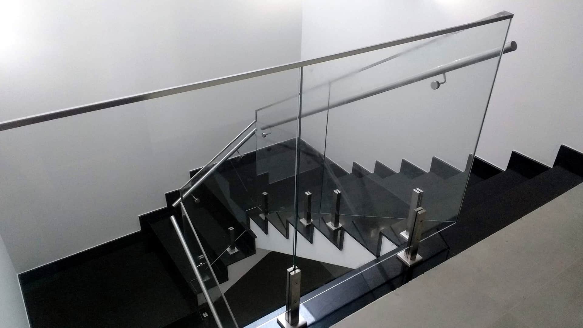 Escada em granito preto vista do alto com guarda-corpo de vidro
