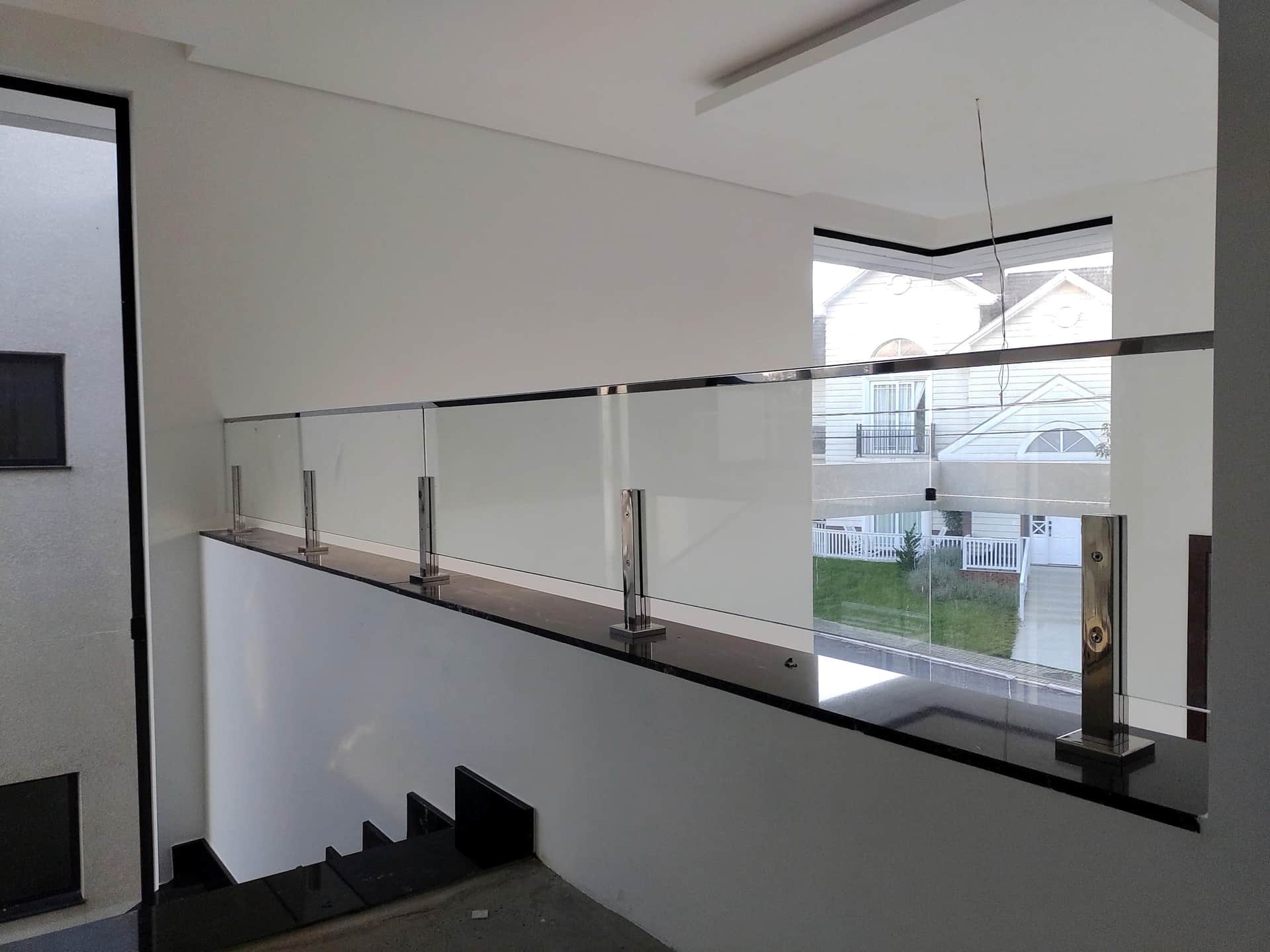 Guarda-corpo de vidro do mezanino com colunas em inox sobre borda escura