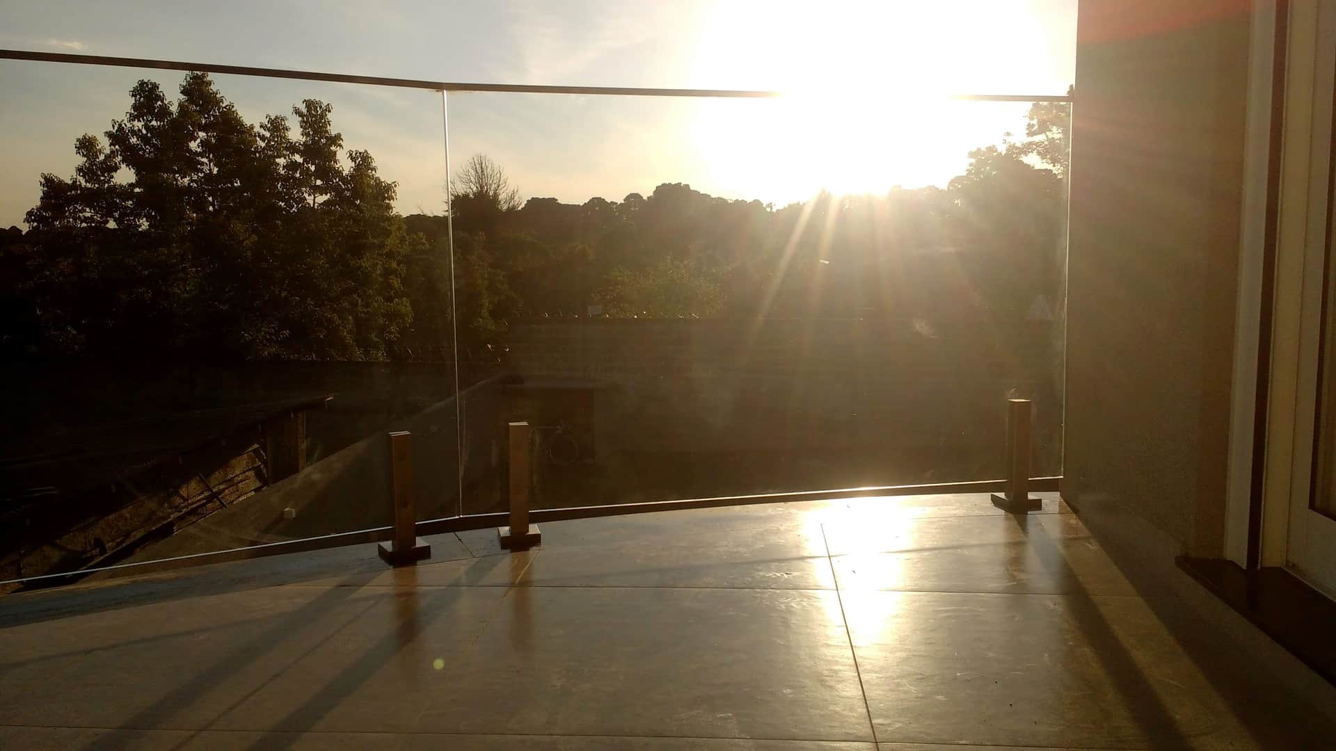 Terraço com guarda-corpo de vidro contra o pôr do sol